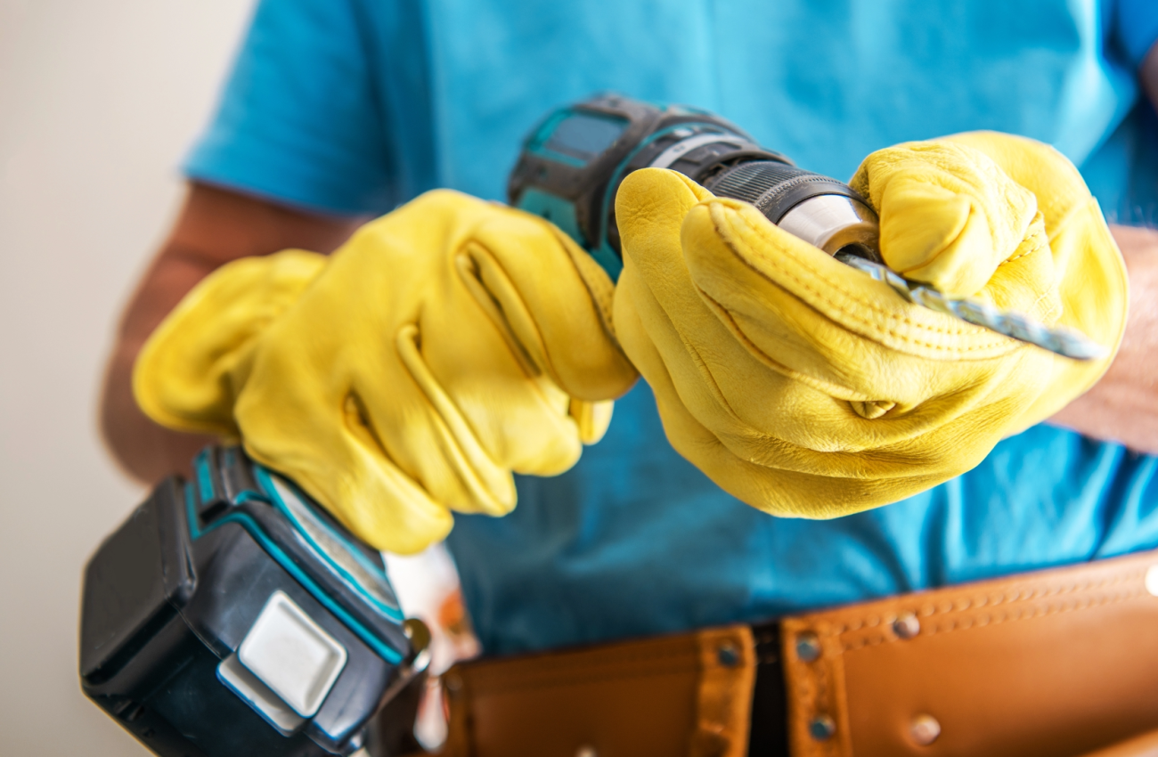 Handwerker mit Handschuhen hält Werkzeug – Hausmeisterservice für Reparaturen vor Ort